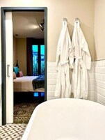 Una habitación de hotel con una cama, un baño con bañera y vistas a la ciudad por la ventana.