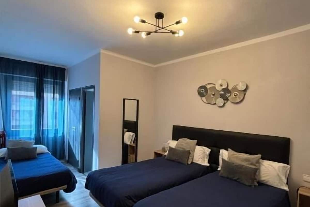 Une chambre d’hôtel avec deux lits, une télévision, un bureau et un lustre moderne.