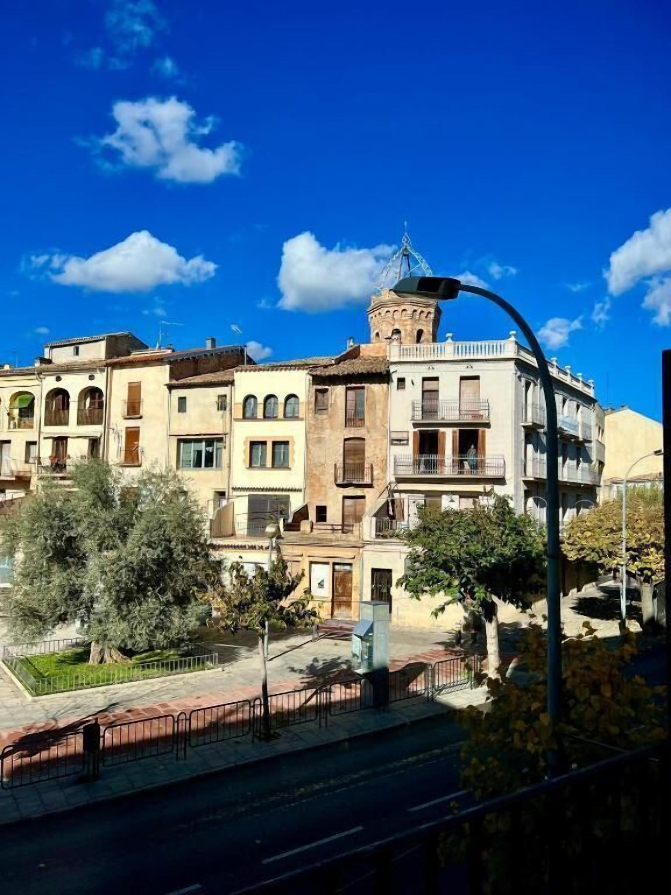 A row of traditional buildings with balconies, a street lamp, and a clear blue sky.