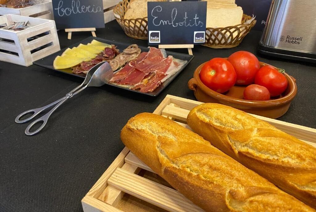 Una mesa con diversos alimentos, como pan, tomates y carne.
