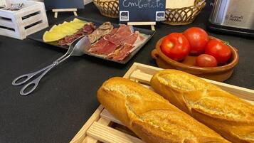 Una mesa con diversos alimentos, como pan, tomates y carne.