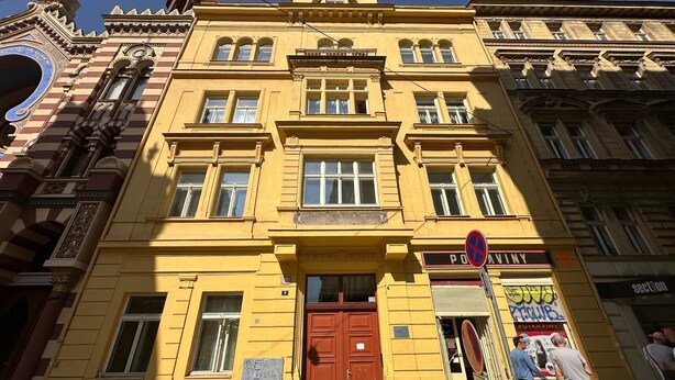 A yellow building with a large brown door and multiple windows.