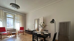 A dining area with a wooden herringbone floor, a black dining table set for four, and a modern stainless steel refrigerator.