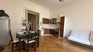 A modern kitchen with wooden cabinets, a dining area with a table and chairs, and a white sofa.