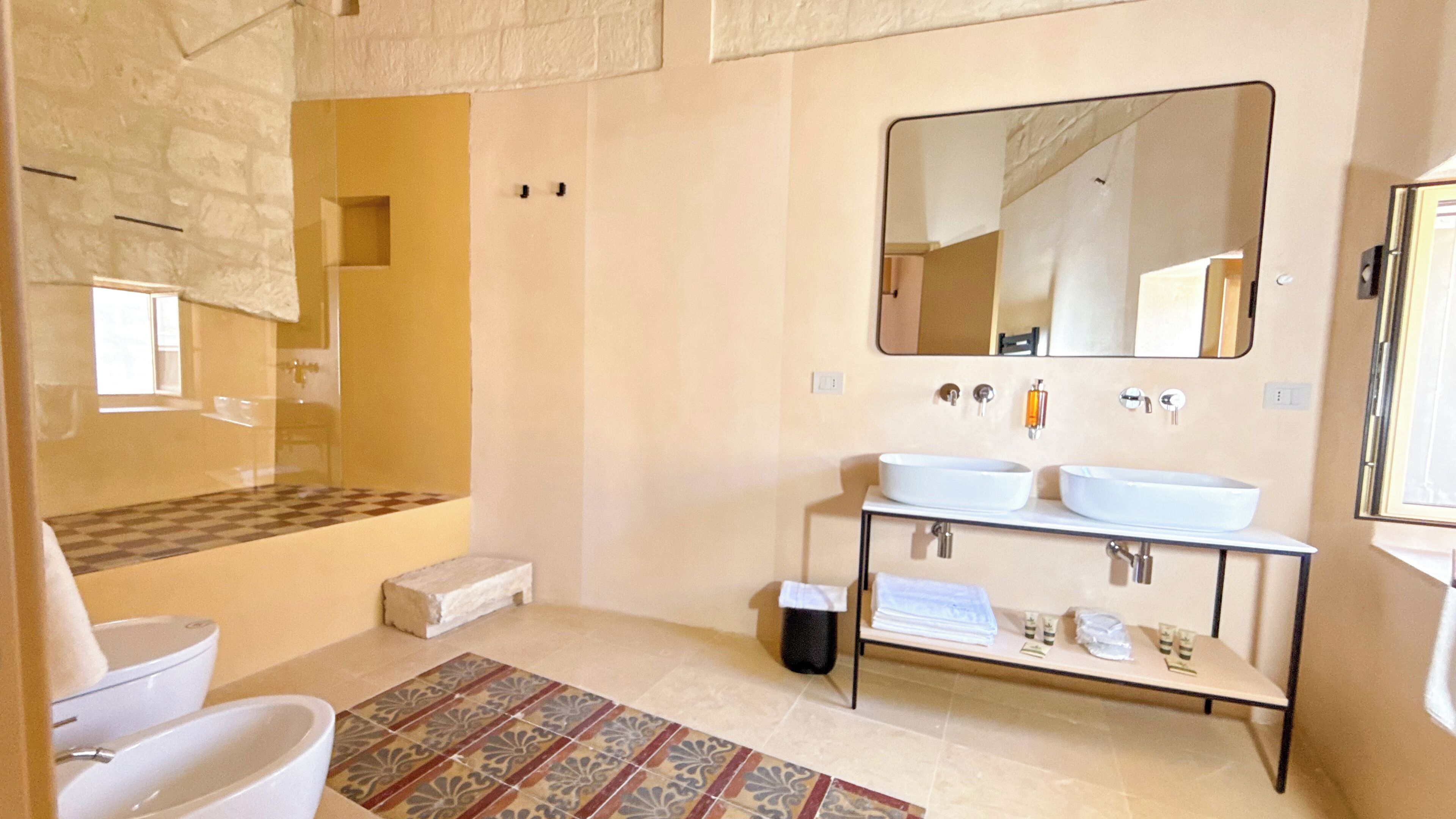 A bathroom with two sinks, a large mirror, and a shower area.
