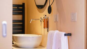 A bathroom with a white sink, a towel rack with a white towel, a hairdryer mounted on the wall, and a mirror.