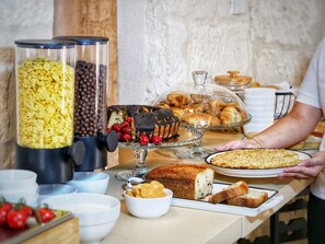 A buffet with various food items including cereal, chocolate-covered cherries, pastries, and bread. - PALAZZO VIGILARIUM - Boutique Rooms  (Uggiano la Chiesa)