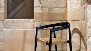 A corner of a room with a stone wall, a small wooden chair, and a tiled floor. - PALAZZO VIGILARIUM - Boutique Rooms (Uggiano la Chiesa)