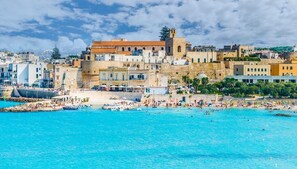 A coastal town with a historic building, a beach, and clear blue waters. - PALAZZO VIGILARIUM - Boutique Rooms  (Uggiano la Chiesa)