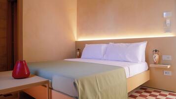 Een hotelkamer met een bed, nachtkastje en een rode vaas.
