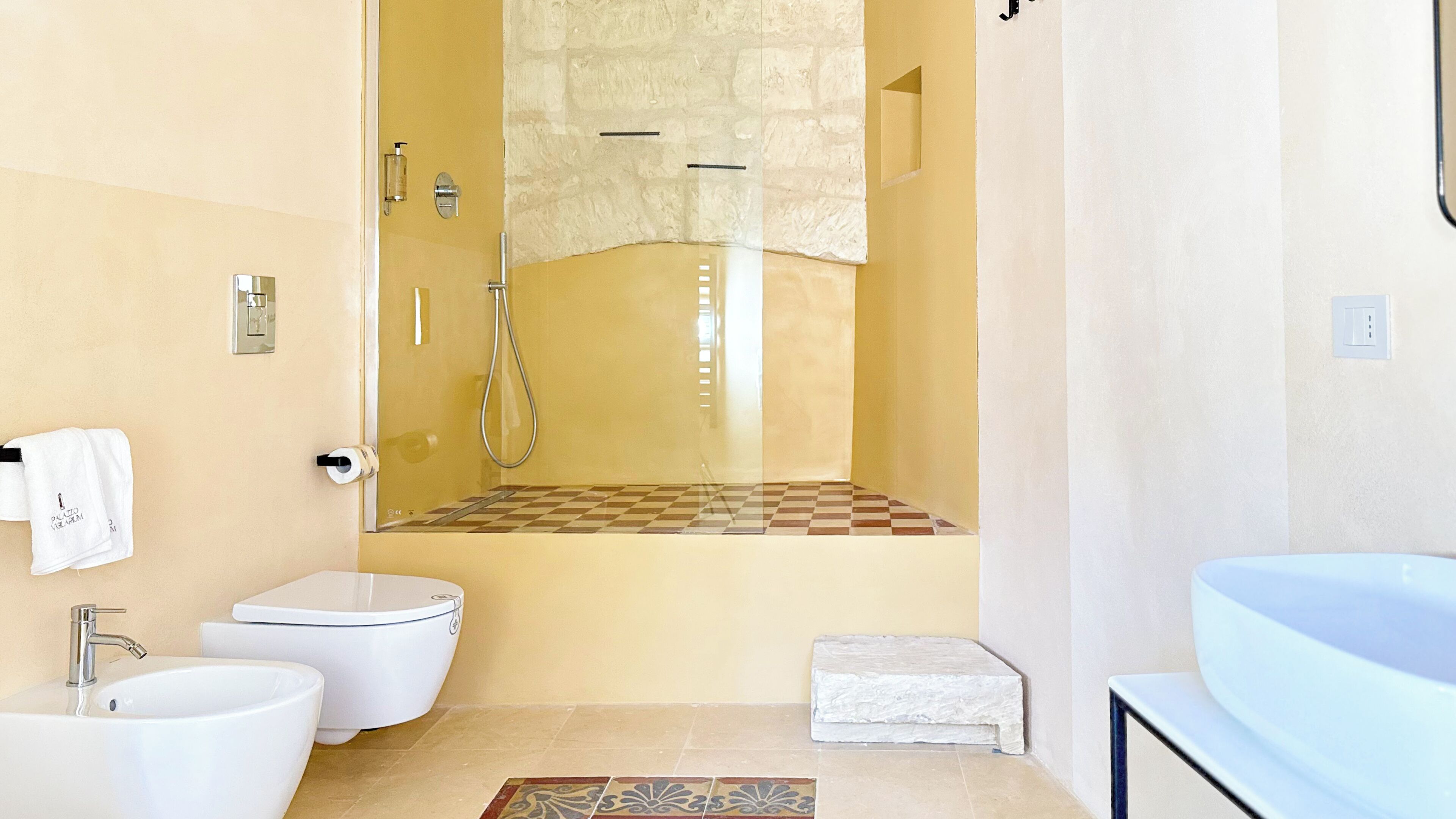 A bathroom with a toilet, sink, and shower area.