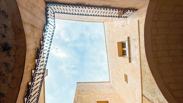 A narrow alleyway with a view of the sky through a small window, surrounded by old buildings with a rustic appearance. - PALAZZO VIGILARIUM - Boutique Rooms (Uggiano la Chiesa)
