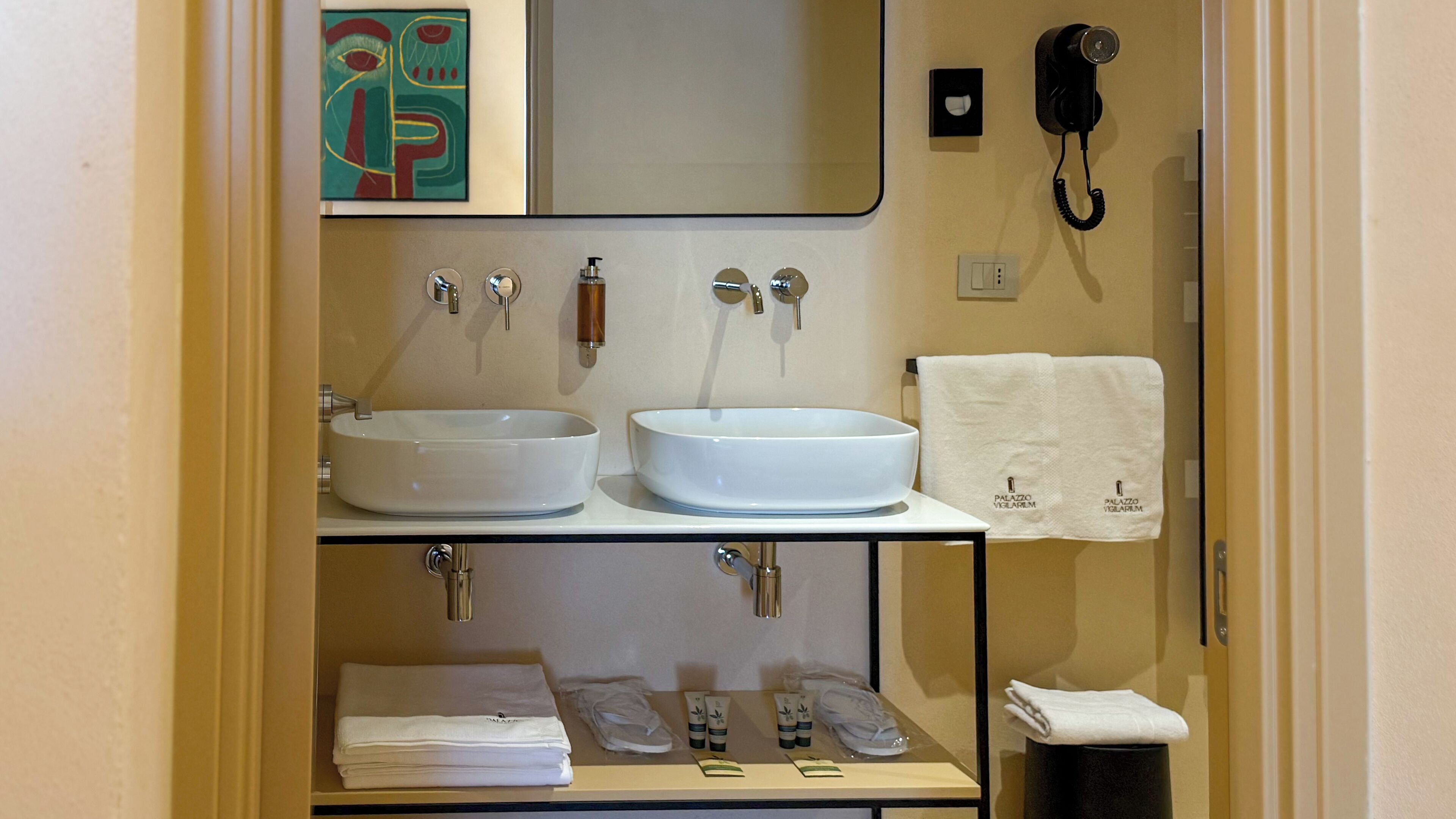 A bathroom with two sinks, a mirror, a towel rack, and a phone.