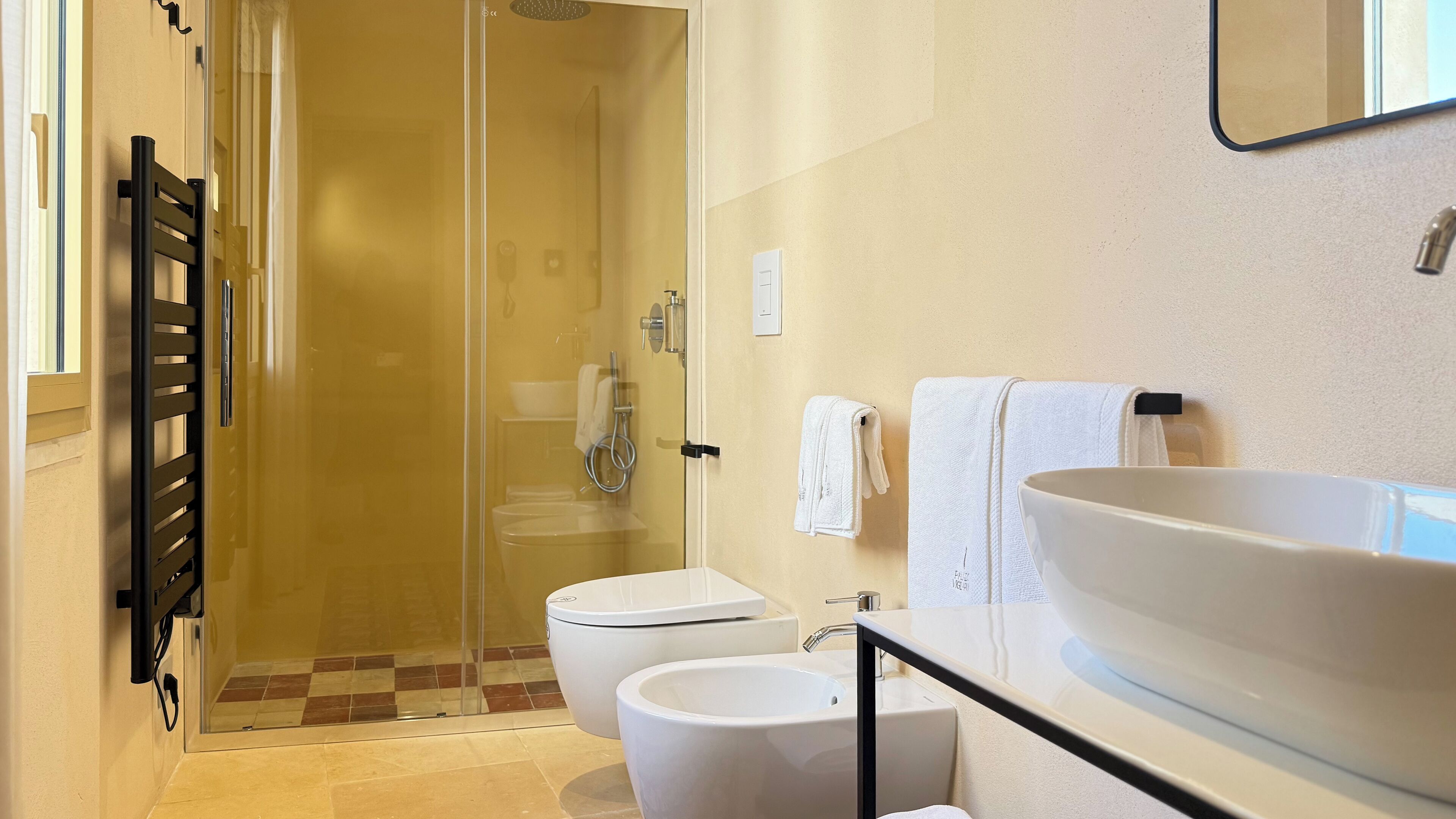 Une salle de bain dotée d’une douche à parois de verre, de toilettes, d’un lavabo et d’un grand miroir.