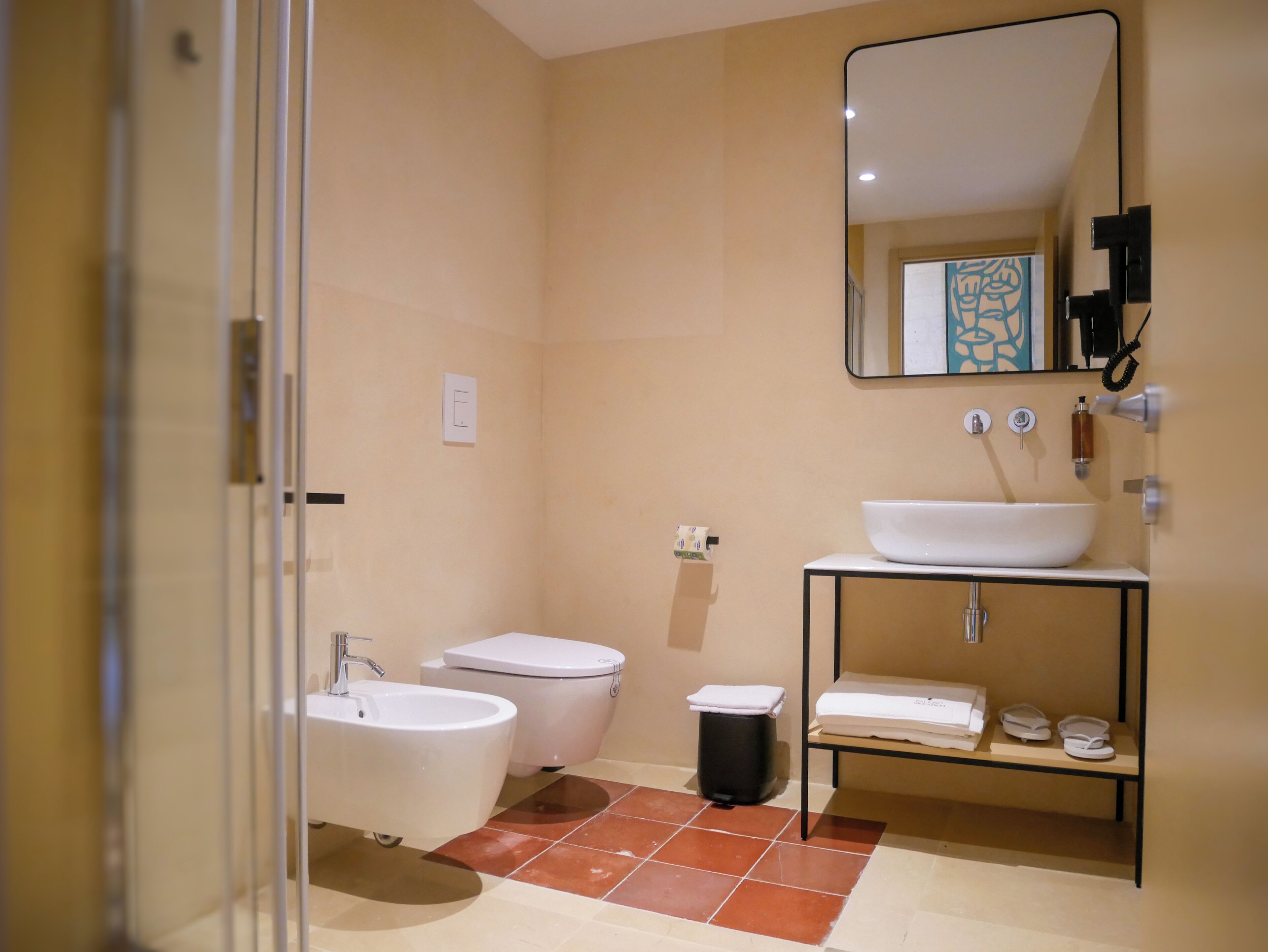 Un baño moderno con cabina de ducha de vidrio, un lavabo blanco, un inodoro y un mueble de tocador con espejo.