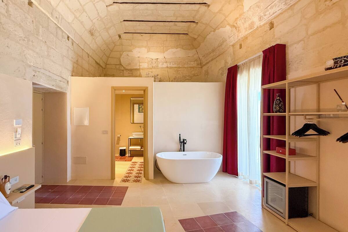 Une salle de bain moderne avec une baignoire sur pieds, une douche et un meuble-lavabo. On y trouve également un dressing avec des étagères et une tringle à vêtements.