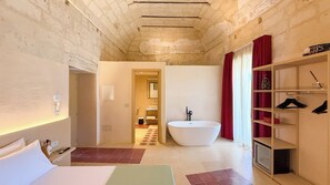 A modern bathroom with a freestanding bathtub, a shower, and a vanity. There is a walk-in closet with shelves and a hanging rack. - PALAZZO VIGILARIUM - Boutique Rooms  (Uggiano la Chiesa)