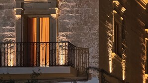A stone building with a balcony and a window with curtains. - PALAZZO VIGILARIUM - Boutique Rooms (Uggiano la Chiesa)
