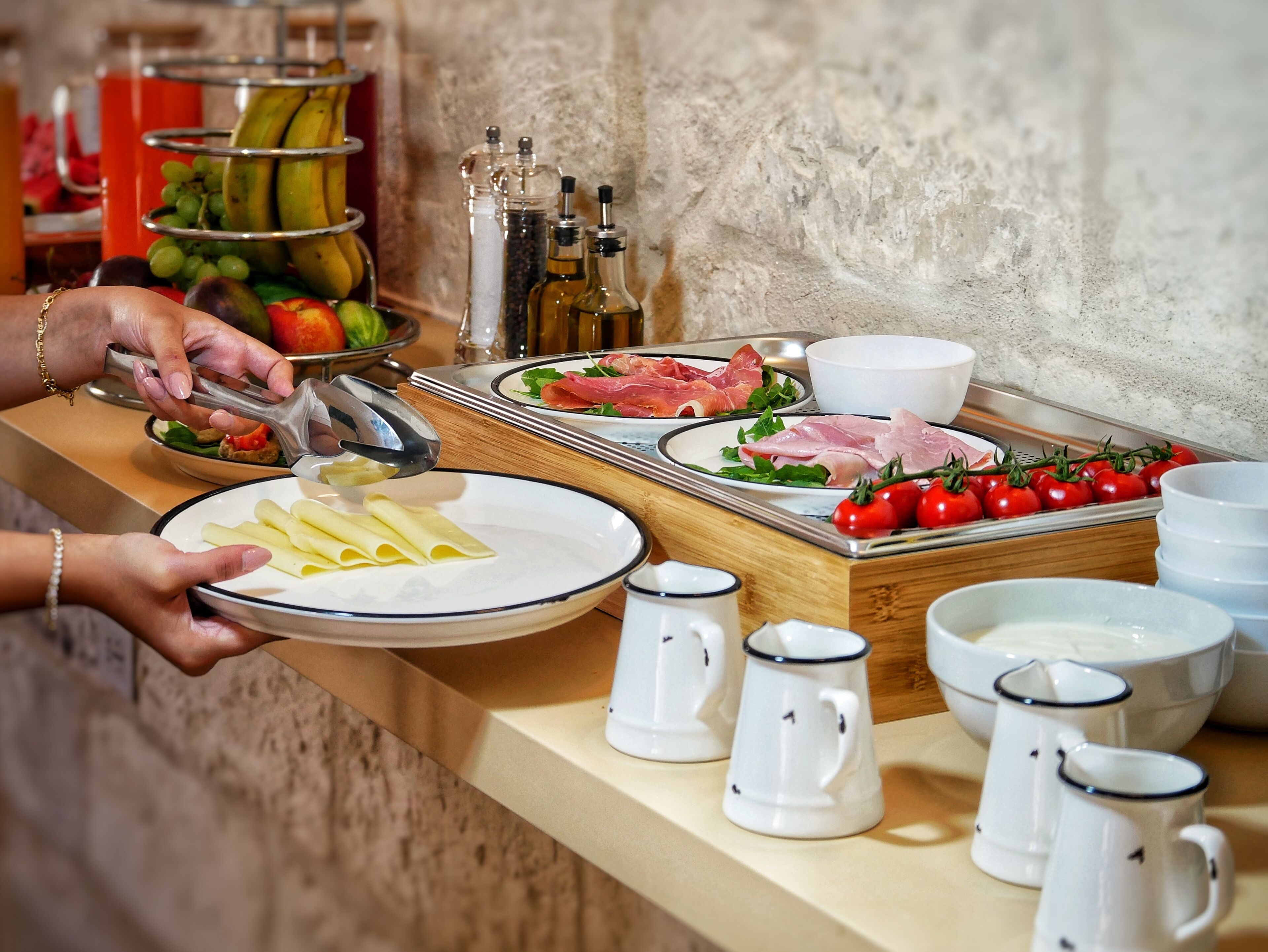 A buffet setup with plates of food, including pasta, meats, and vegetables, and condiments.