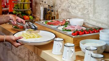 A buffet setup with plates of food, including pasta, meats, and vegetables, and condiments.