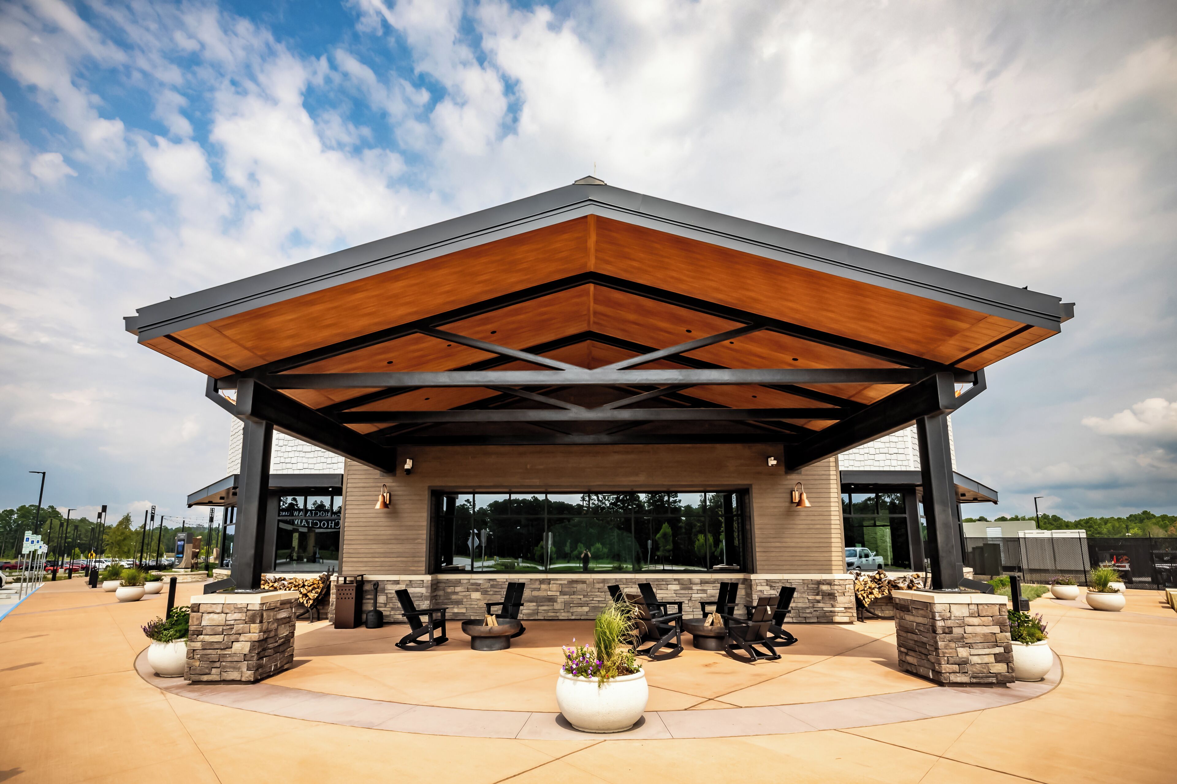 A modern building with a covered patio area, outdoor seating, and large windows.