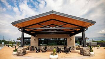 A modern building with a covered patio area, outdoor seating, and large windows.