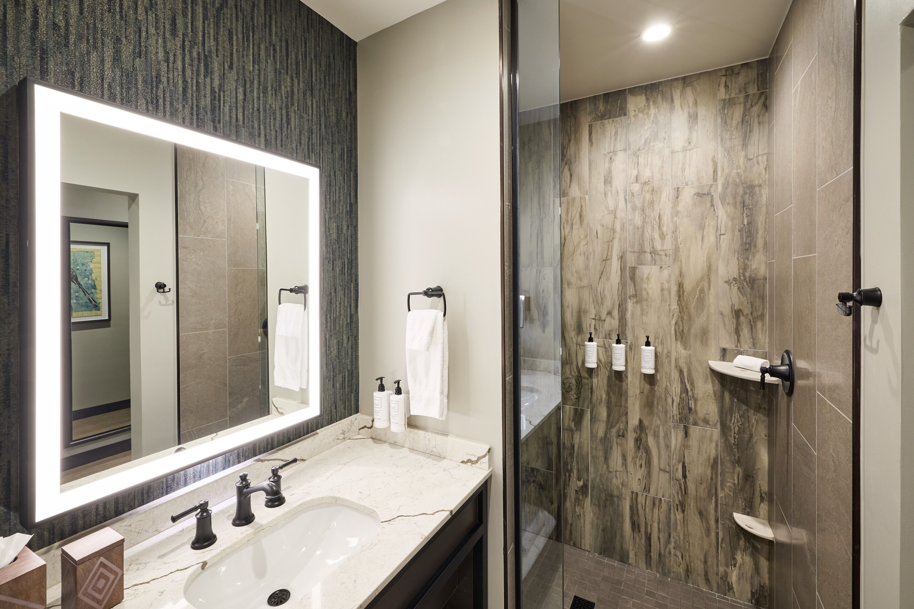Un baño moderno con un espejo grande, un lavabo y una zona de ducha.