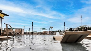 A swimming pool with lounge chairs and umbrellas, surrounded by a clear sky. - Choctaw Landing Casino & Resort, Trademark Collection by Wyndham (Hochatown)