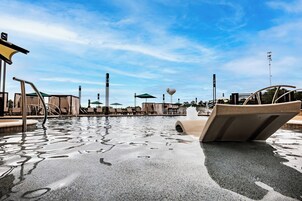 Una piscina al aire libre, camas de piscina con cargo, sombrillas