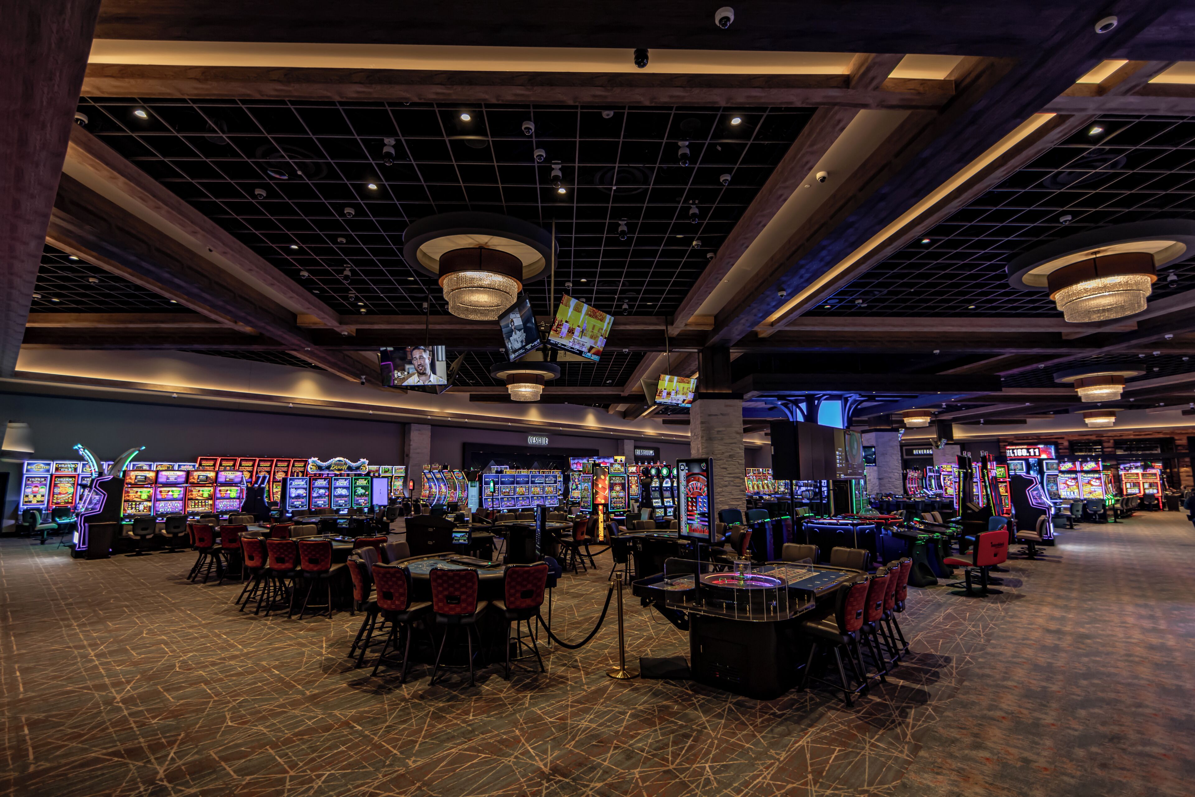 Un casino con máquinas tragamonedas, mesas y sillas.