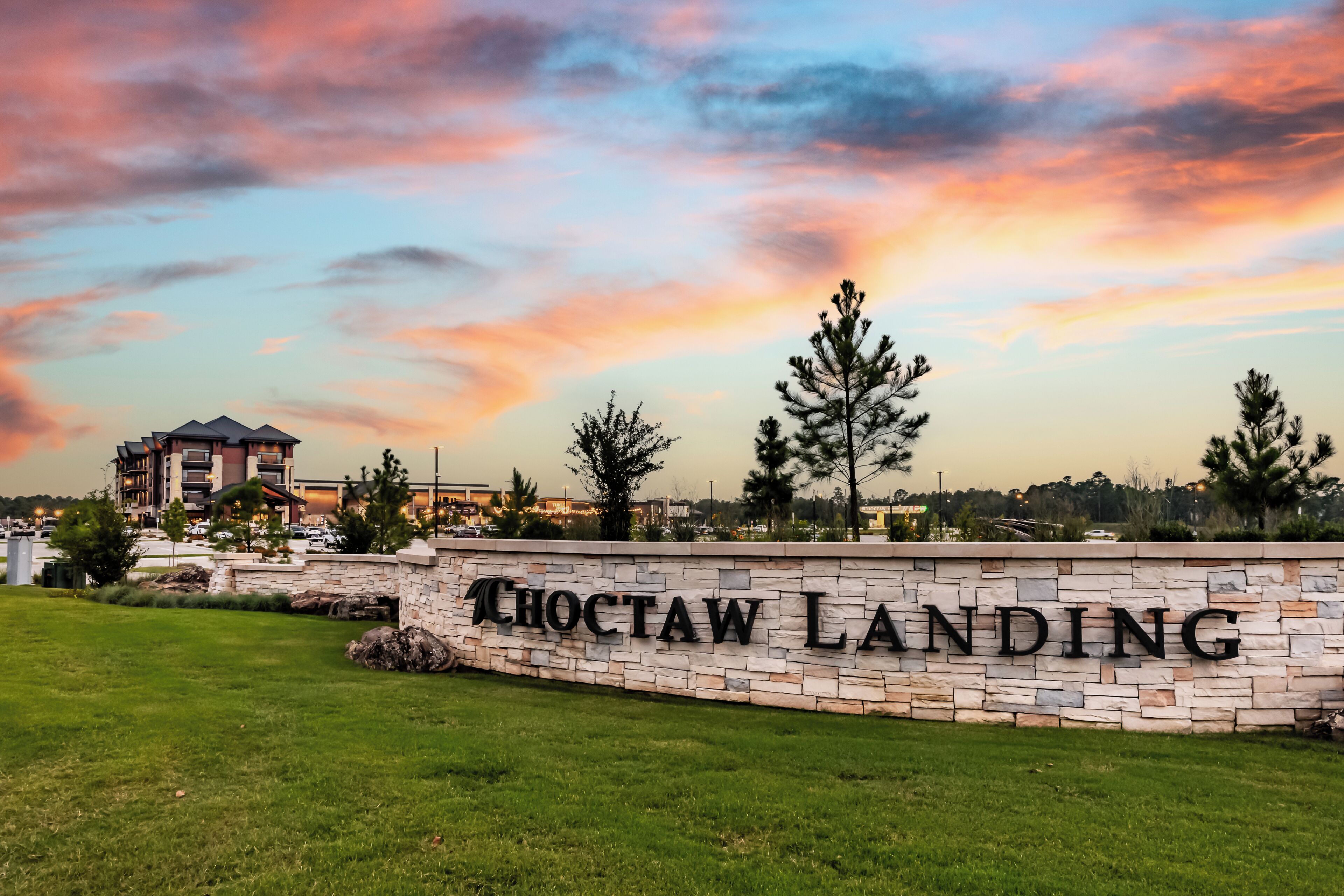 A stone wall with 'CHOCTAW LANDING' signage, a grassy area, and a building in the background.