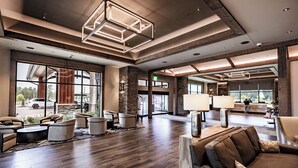 A spacious lobby with a wooden floor, large windows, and modern lighting fixtures. - Choctaw Landing Casino & Resort, Trademark Collection by Wyndham (Hochatown)