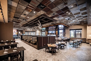 Un restaurant spacieux avec de hauts plafonds, plusieurs espaces aménagés pour s’asseoir et un bar.