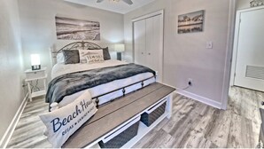 Ein Schlafzimmer mit einem Bett, einer Bank, einem Deckenventilator und Kunstwerken an den Wänden.