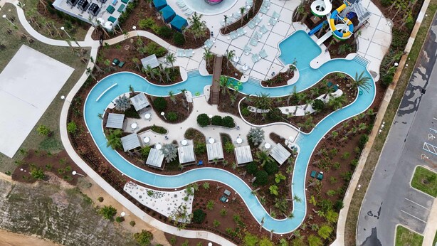 An aerial view of a resort with a winding pool, sun loungers, and a water slide. - Family Friendly 5Bd Near Disney Windsor Cay 16136 (Clermont)