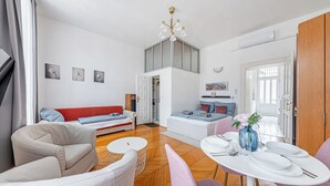 En moderne stue med sofa, stole, et spisebord og en trappe til en etage ovenover.