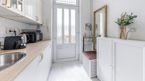 Et moderne køkken med hvide skabe, kaffemaskine, brødrister og vask.