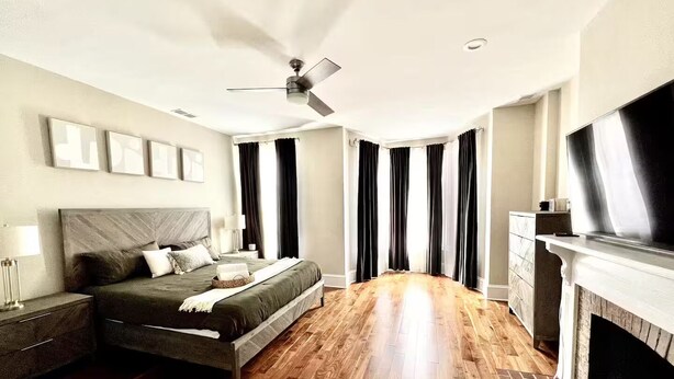 A bedroom with a bed, a nightstand, a dresser, a fireplace, and a ceiling fan. - LUXURIOUS DC ESTATE, BEST LOCATION BLOCK AWAY FROM 14TH/U ST NW W/ 2 CAR PARKING (Washington)