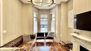 A spacious living room with a large sectional sofa, a fireplace, and a television mounted on the wall. - LUXURIOUS DC ESTATE, BEST LOCATION BLOCK AWAY FROM 14TH/U ST NW W/ 2 CAR PARKING (Washington)