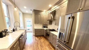 A modern kitchen with wooden cabinets, stainless steel appliances, and a marble countertop. - LUXURIOUS DC ESTATE, BEST LOCATION BLOCK AWAY FROM 14TH/U ST NW W/ 2 CAR PARKING (Washington)