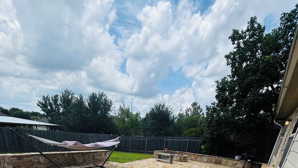 A stone patio with a hammock, a fire pit, and a barbecue grill. - Spacious 4-bedroom house in fantastic Buda with WiFi, game /fitness room& more! (Buda)