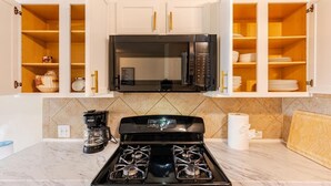 A kitchen with white cabinets, a black stove, a microwave, and a coffee maker. - Spacious 4-bedroom house in fantastic Buda with WiFi, game /fitness room& more! (Buda)