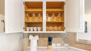 A kitchen with white cabinets, a marble countertop, and a wooden shelf with wine glasses and cups. - Spacious 4-bedroom house in fantastic Buda with WiFi, game /fitness room& more! (Buda)