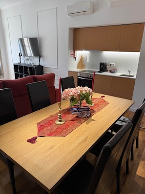 A dining area with a wooden table, chairs, a vase with flowers, and a red placemat.