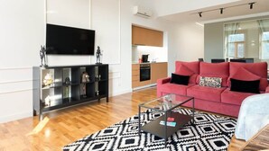 A modern living room with a red sofa, a glass coffee table, and a patterned rug.
