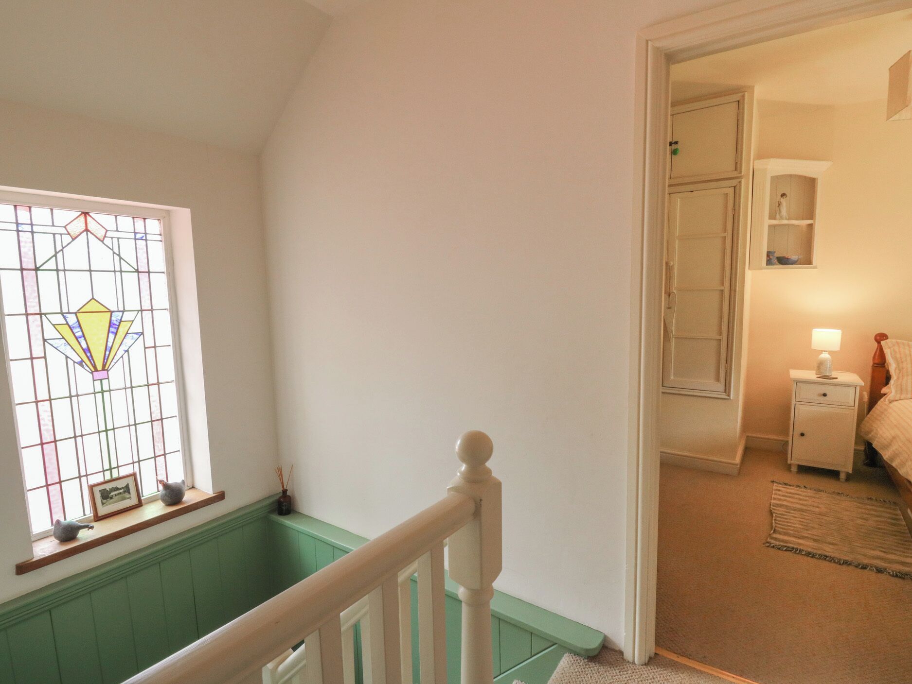 A staircase with a green wainscoting and a white railing leading to a bedroom.
