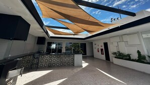 Un intérieur moderne avec un plafond haut, des motifs géométriques sur les murs et un espace d’accueil central doté d’un comptoir et de sièges.