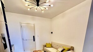 Un salon moderne avec un canapé blanc, une table basse et un luminaire au plafond original.