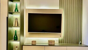 Un salon moderne doté d’un téléviseur à écran plat fixé au mur, d’une bibliothèque intégrée agrémentée d’objets décoratifs et d’une console au design minimaliste.