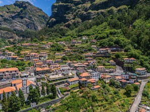 A hillside village with terraced houses, narrow roads, and a prominent rocky mountain in the background. - Cora o da Madeira - Quebrada by Homie (Camara de Lobos)